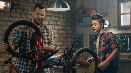 父子俩正在修理自行车的轮子