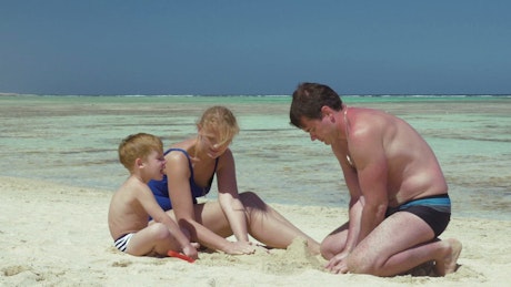 Father building a sand castle with his family