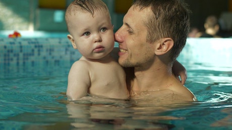 Father hugging his son in the pool.