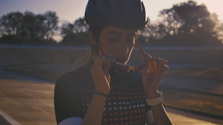 Female cyclist putting on sunglasses before training.