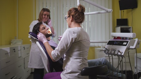 Female Dentist polishing teeth.