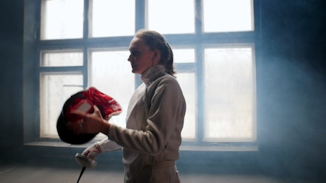 Female fencer stands in fighting pose.