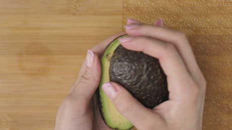 Female hands cutting an avocado in the kitchen.