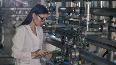 Female worker checks pressure levels in machines.