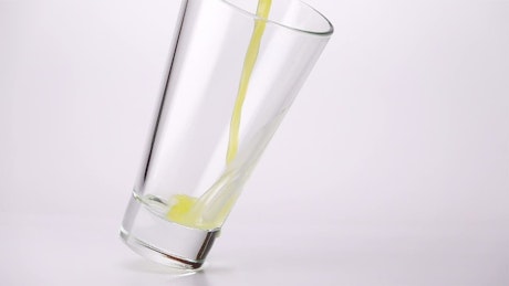 Filling a glass with juice on a white background.