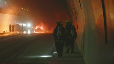 Firefighters working inside a dark tunnel.