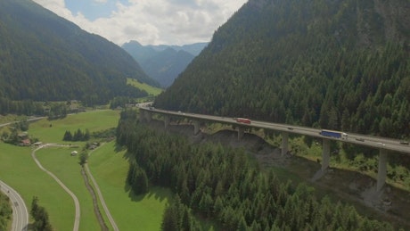 Flying along mountain highway in forested valley.