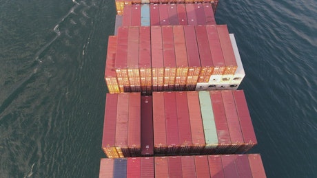 Flying over a cargo ship leaving a port.