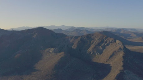 Flying over a large mountain range in an arid climate.