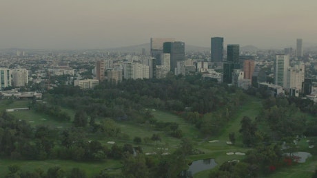 Flying over a large park surrounded by a metropolis