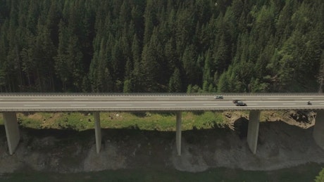 Flyover of tall mountain highway along river.