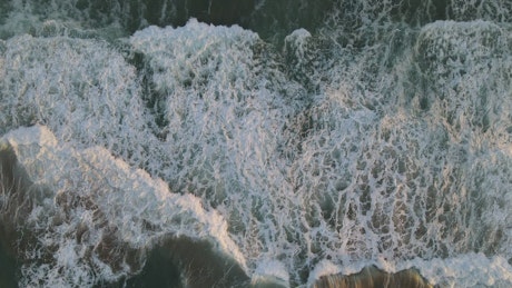 Foamy wave surface on a shoreline from above.