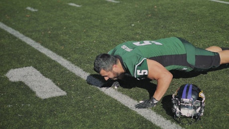 Football player doing push-ups.