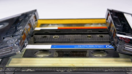 Four audio cassettes rotating on a white surface.