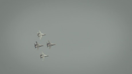 Four fighter jets flying through an overcast sky.