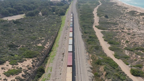 Freight train moving along the tracks next to the ocean.