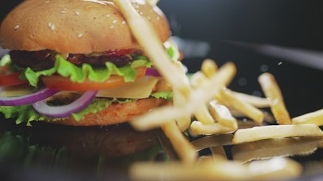 French fries falling in slow motion next to a burger.