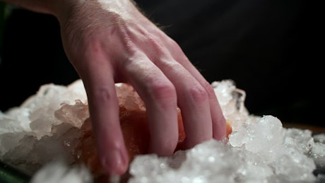 Fresh slice of salmon being picked up from a pile of ice.