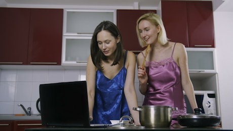 Friends cooking with the help of a video tutorial