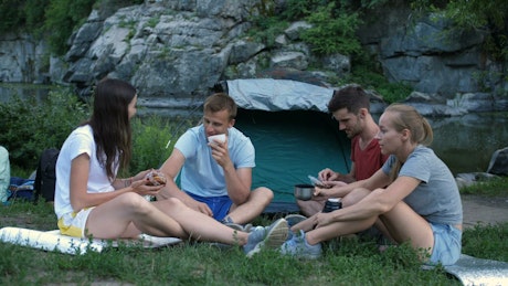 Friends eating while camping in a park.