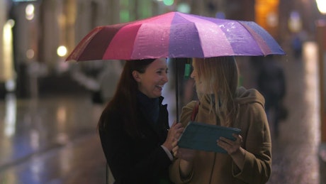 Friends standing under an umbrella.
