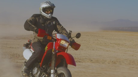 Frontal tracking shot of a biker in the desert.