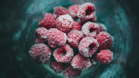 Frozen raspberries inside a big glass.