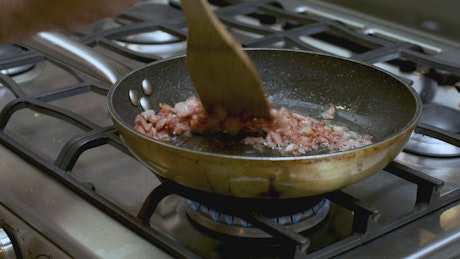 Frying diced bacon in a skillet.