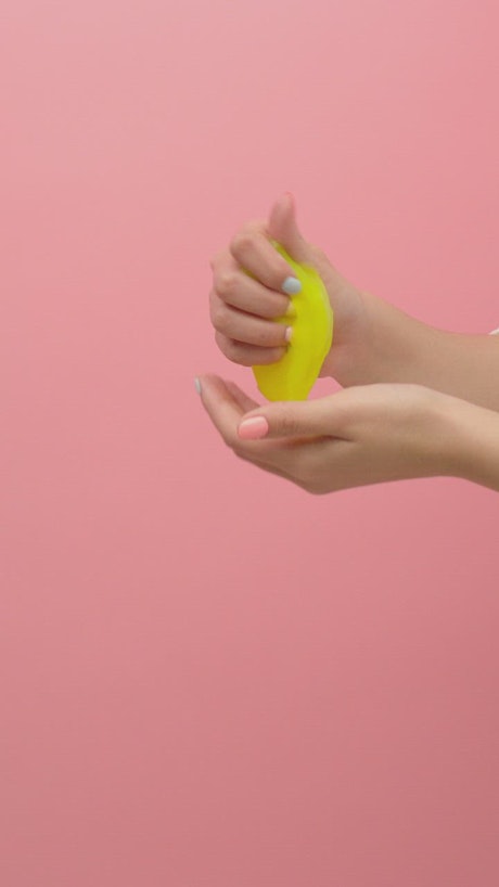 Funny and slippery yellow slime in the hands of a woman.