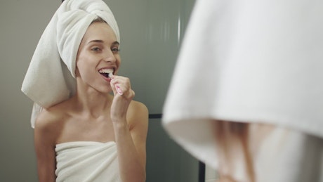 Funny woman brushes teeth after shower.