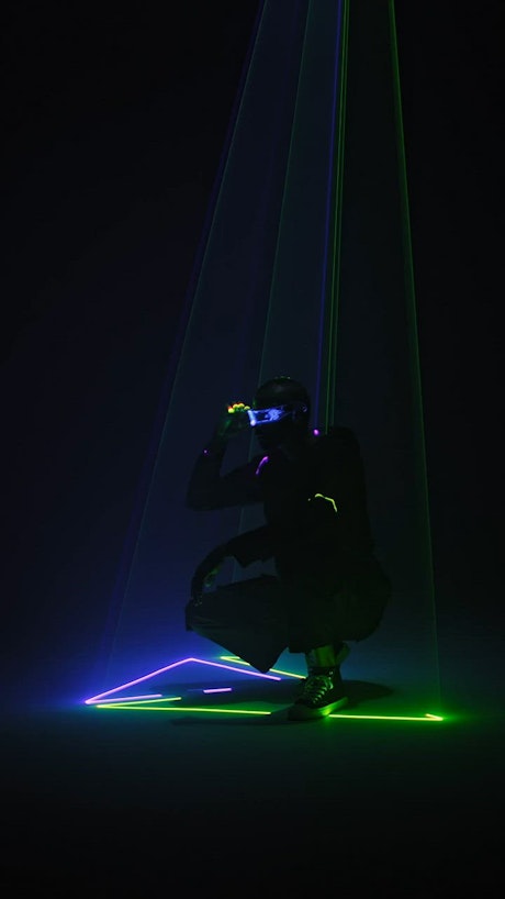 Futuristic looking man using sunglasses is surrounded by lasers.