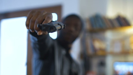 Gangster aiming with a gun at the camera.