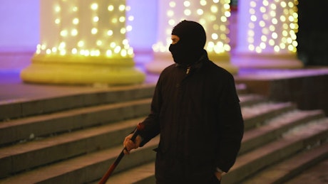 Gangster walking with a baseball bat at night.
