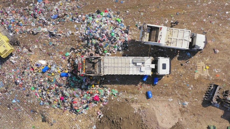 Garbage trucks dumping rubbish in landfill.