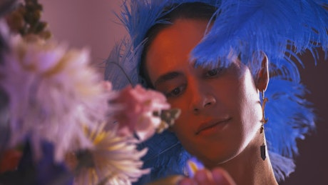 Gay man dressed feminine appreciating flowers.