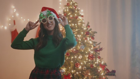 Girl dances happily in the living room by the Christmas tree.
