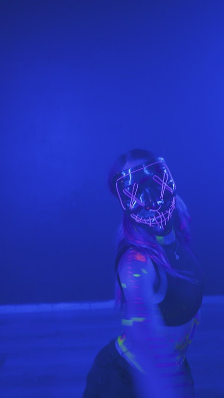 Girl dancing with a mask under a blue light