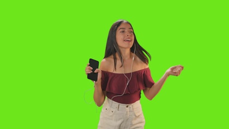 Girl dancing with her earphones on a green background.