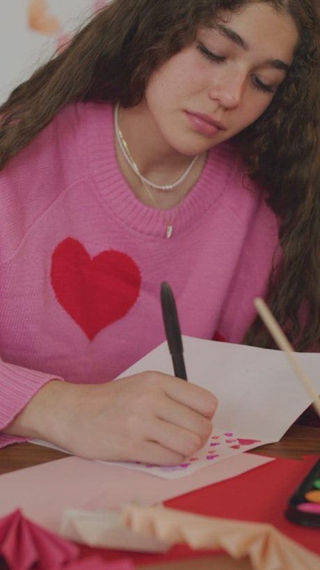 Girl decorating a valentine card with hearts.