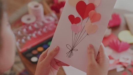 Girl decorating a Valentine's card with a kiss.