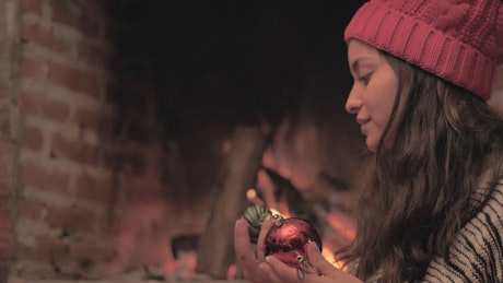 Girl decorating Christmas tree next to a fireplace