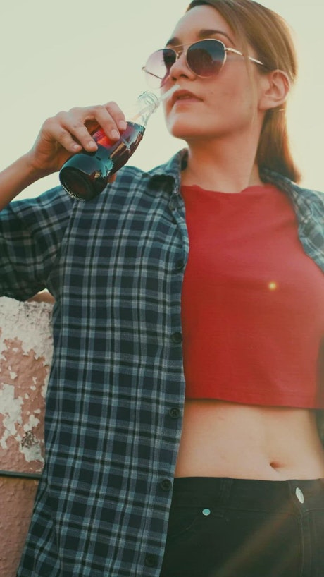 Girl drinking soda from a bottle with a straw