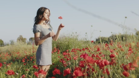 Girl enjoys the open air and the flowers in the countryside.