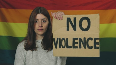 Girl holds a No Violence sign in front of the peace flag.