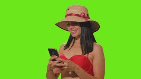 Girl in beachwear takes a selfie on green screen.