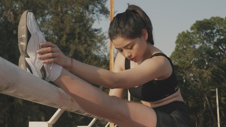 Girl in sportswear stretching her body outdoors.