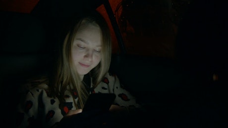 Girl in the back seat of a car, texting