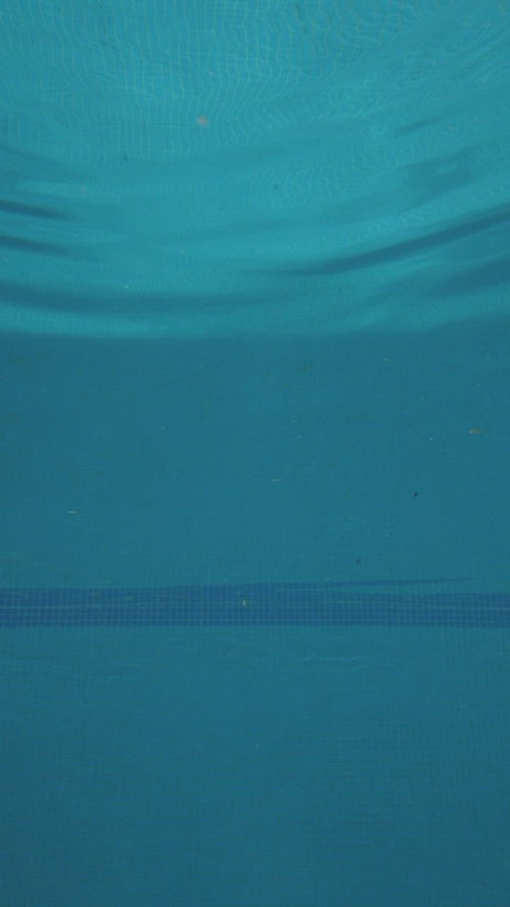 Girl jumps into the pool, seen from underwater.