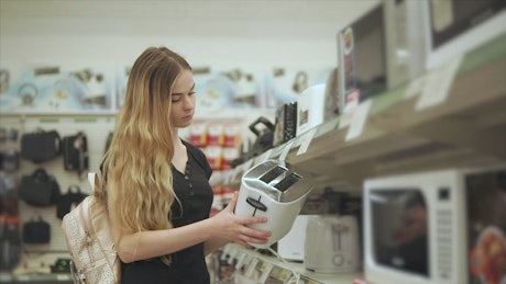 Girl looking for a bread toaster in the supermarket.