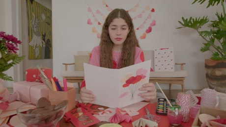Girl looking proudly at a homemade valentine's day card.